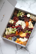 Assorted charcuterie board in a box on a marble surface