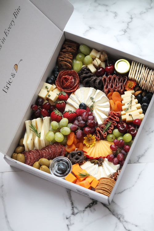 Assorted charcuterie board in a box on a marble surface